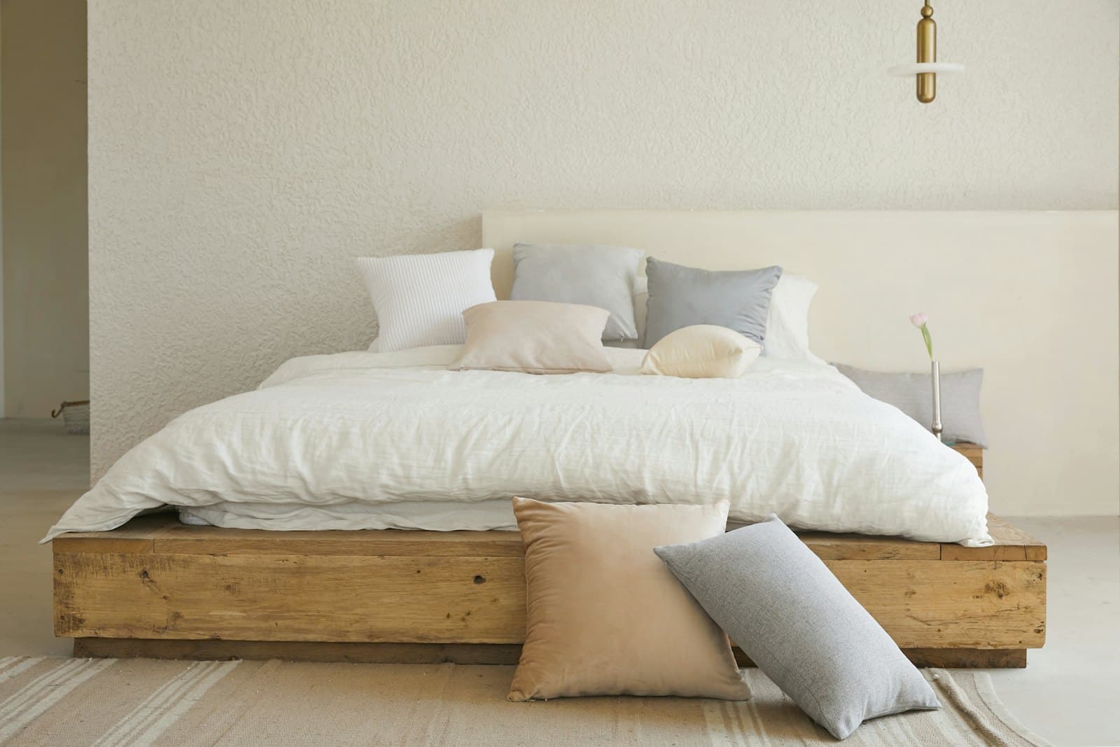 Kamar tidur dengan rangka ranjang kayu dan linen putih
